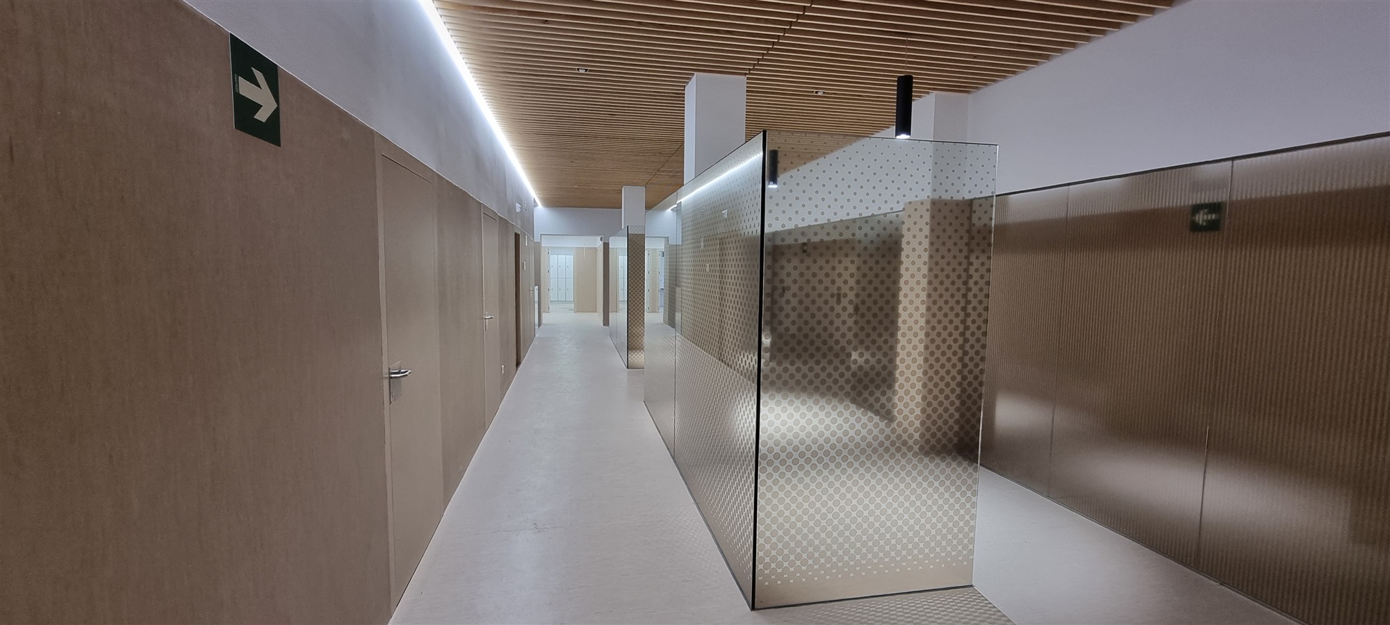 Pasillo de una residencia con paredes de madera y una separación de cristal
