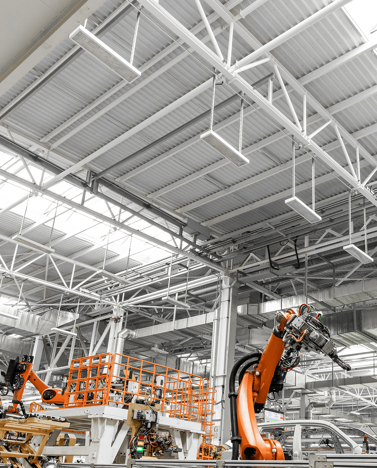 Ingenieria en Pamplona – Introduccion Interior de una nave industrial de producción con brazos robóticos naranjas